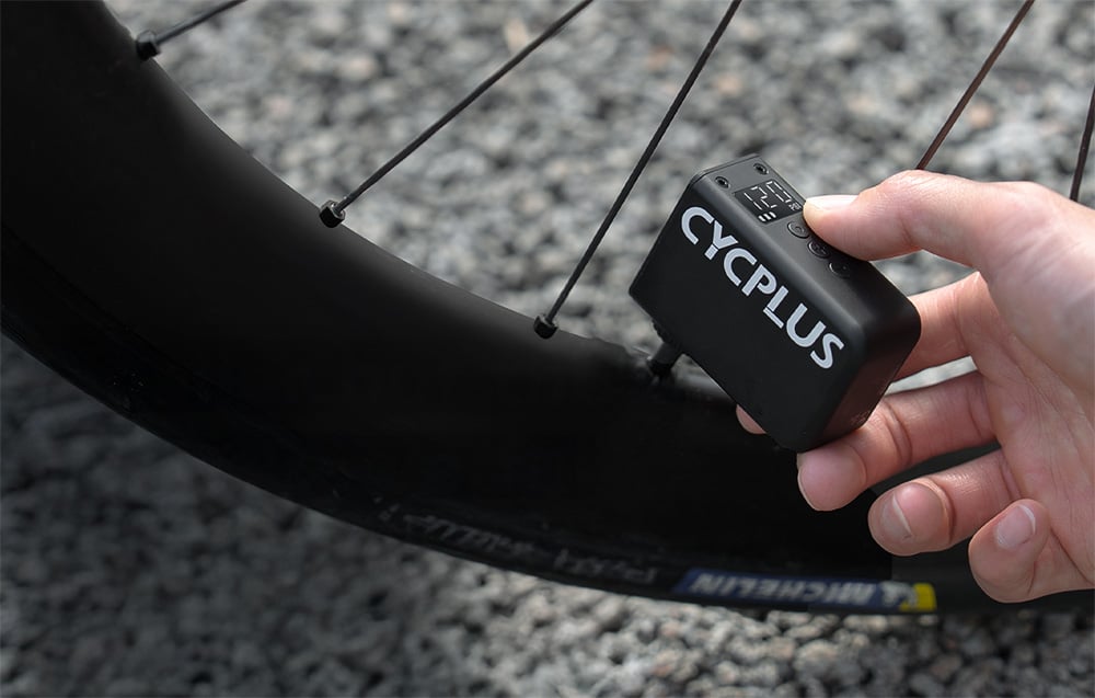Proces bezwysiłkowego pompowania opony roweru szosowego za pomocą mini pompki elektrycznej Cycplus.